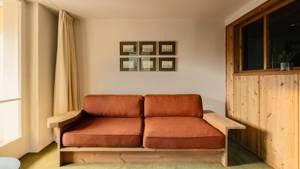 A cozy sofa is placed near the wall, with several portraits mounted above it.