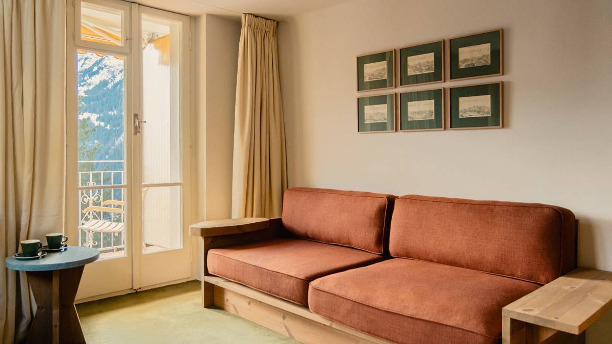 A living space features a cozy sofa set near the glass door, with portraits above.