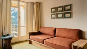 A living space features a cozy sofa set near the glass door, with portraits above.