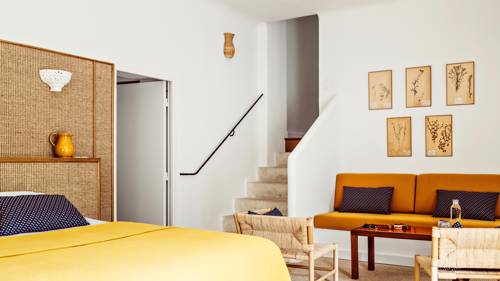 A tidy bedroom features a cozy bed, a sofa beside the stairs, and portraits above.
