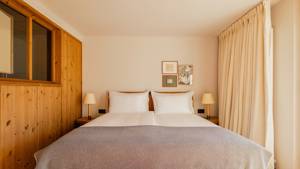 A well-organized bedroom displays a cozy bed, two side tables, and portraits mounted above.
