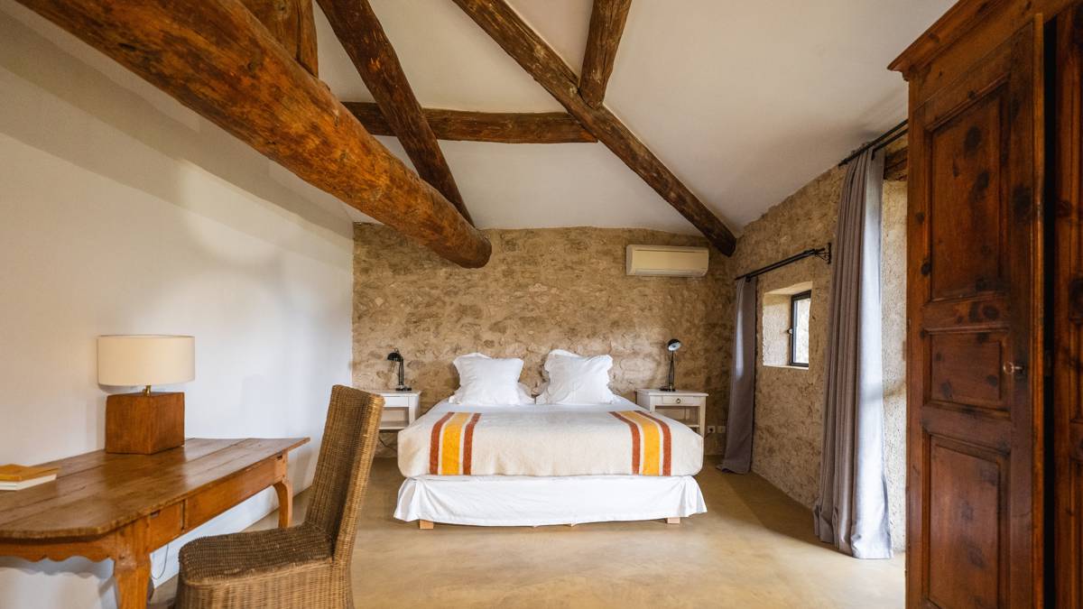 A well-organized bedroom features a bed with side tables holding lamps and a nearby chair.