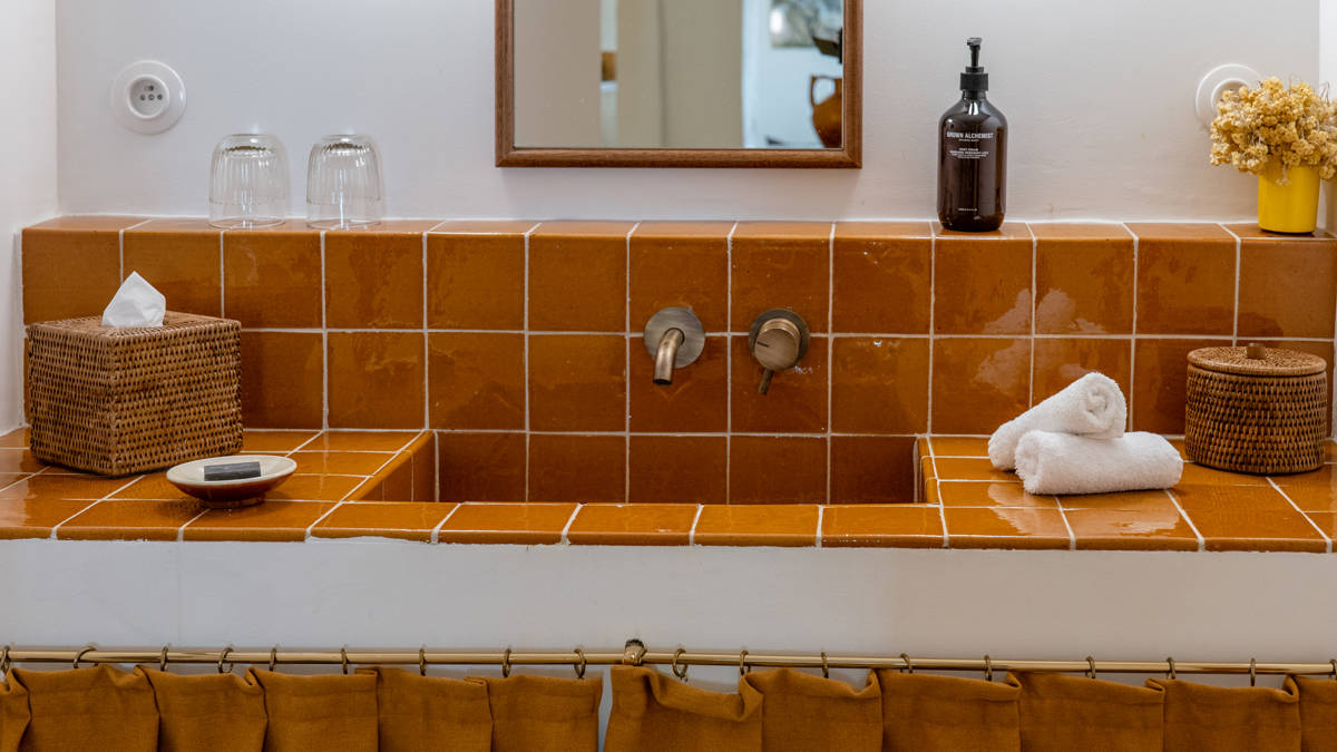 A clicked photo displays an orange-colored washbasin countertop with a neat and vibrant finish.