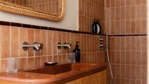 Neatly arranged bottles line the washroom rack, with a mirror mounted above washbasin.