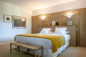A well-organized bedroom features a cozy bed with two portraits mounted on the left wall.