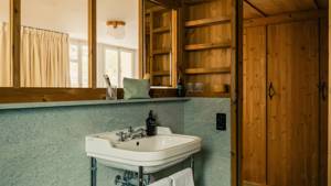 A large mirror is mounted above the washbasin in the bathroom, beautifully reflecting the space.