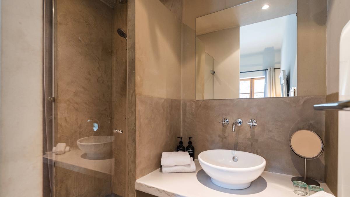 A clicked photo of a neat bathroom features a rectangular mirror above the washbasin.