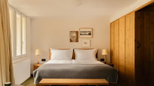 A well-organized bedroom features a cozy bed, two side tables, and portraits above.