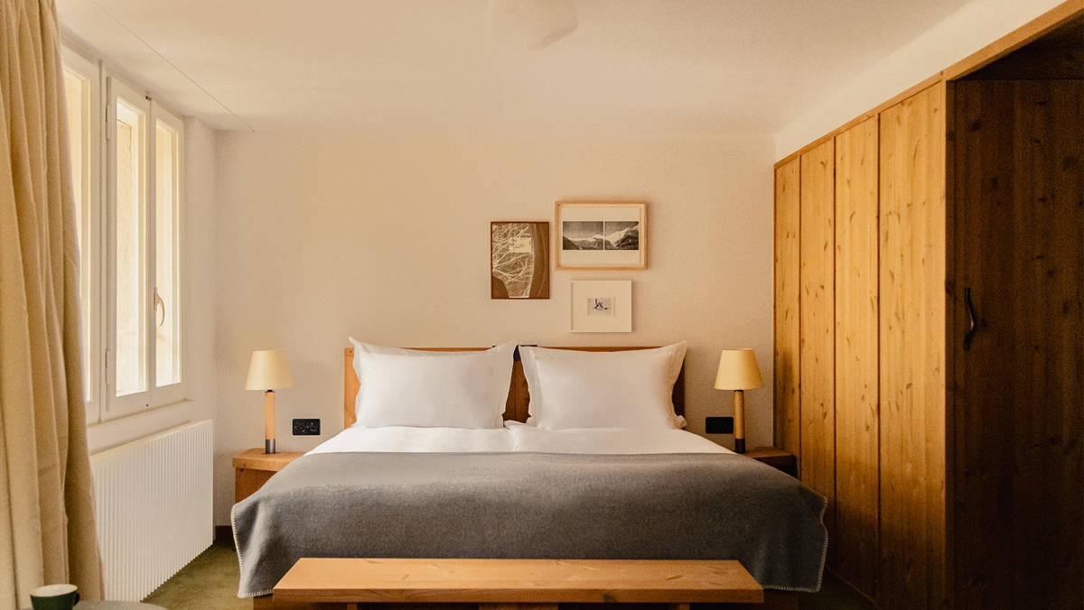 A well-organized bedroom features a cozy bed, two side tables, and portraits above.