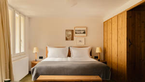 A well-organized bedroom features a cozy bed, two side tables, and portraits above.