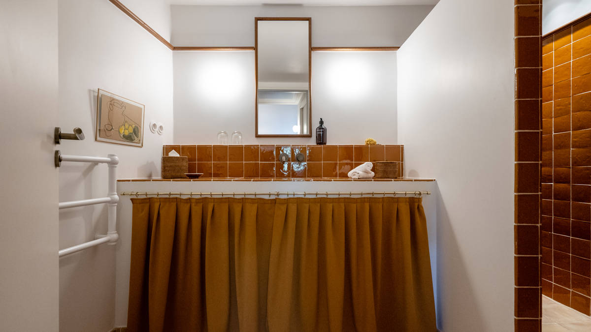 A clicked photo of the bathroom shows a long mirror mounted above the washbasin.