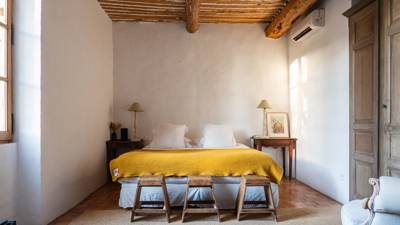 A well-organized bedroom features a cozy bed, two side tables, and three small seats.