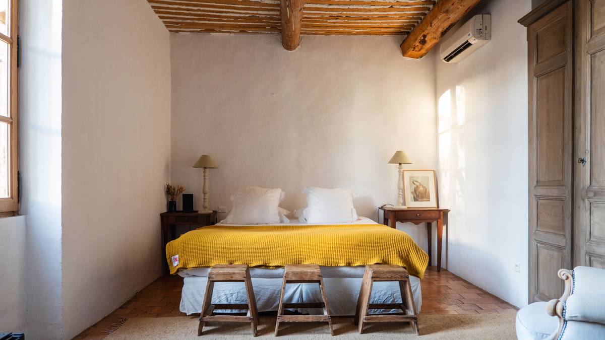 A well-organized bedroom features a cozy bed, two side tables, and three small seats.