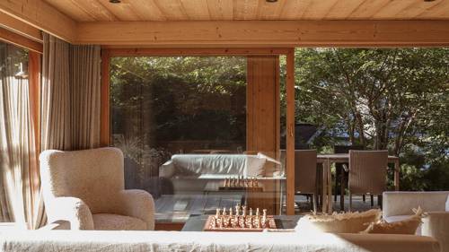 A feather-touch sofa set is placed near the large glass window overlooking lush greenery.