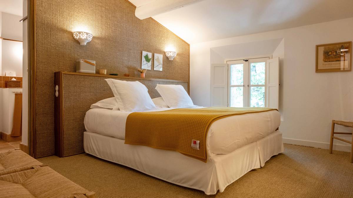 A well-organized bedroom features a cozy bed with a portrait mounted on the right wall.
