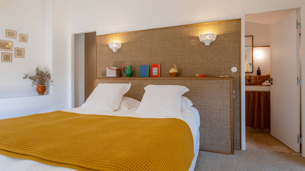 A well-organized bedroom features a cozy bed with some portraits mounted on the left wall.