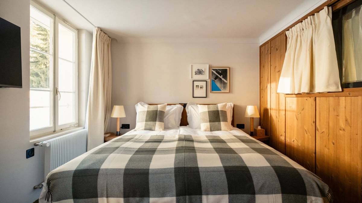 A well-organized bedroom features a cozy bed, two side tables, and portraits mounted above.