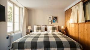 A well-organized bedroom features a cozy bed, two side tables, and portraits mounted above.