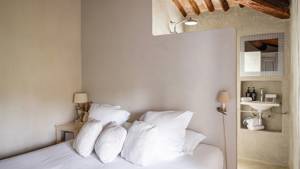 A tidy bedroom features a cozy bed, a side table with lamp, and a visible mirror.