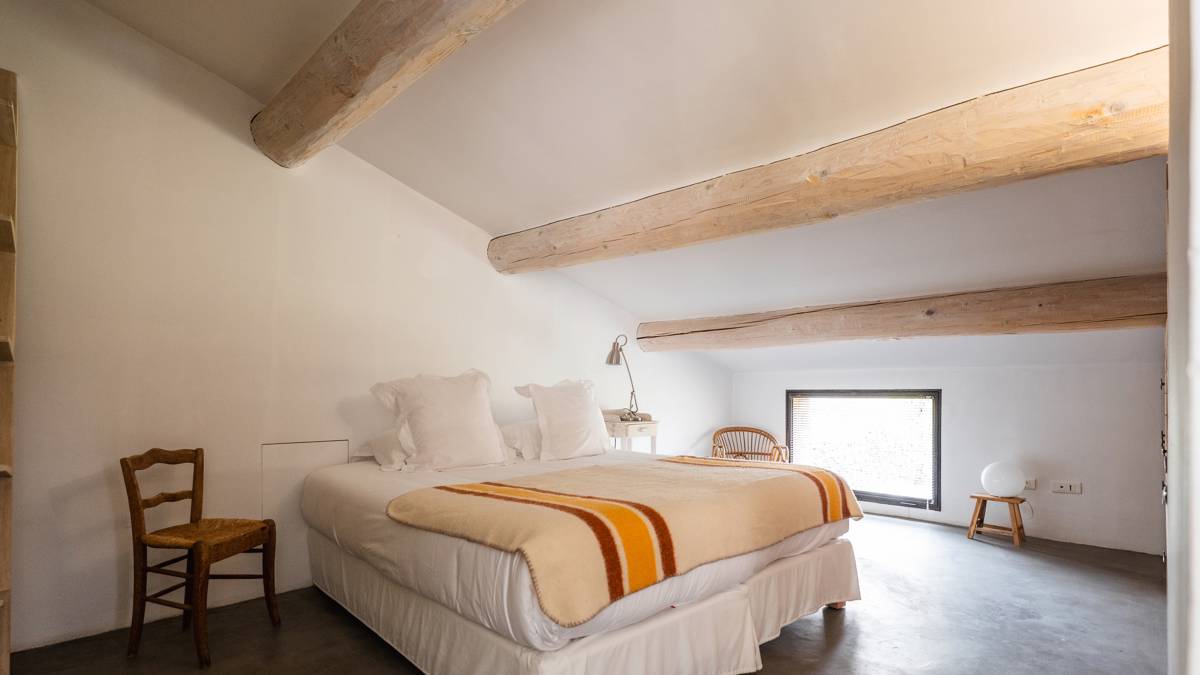 An organized bedroom features a cozy bed with two chairs placed on either side.
