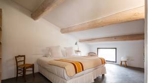An organized bedroom features a cozy bed with two chairs placed on either side.