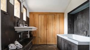 A clicked photo of the bathroom features a bathtub on the right and washbasin on left.