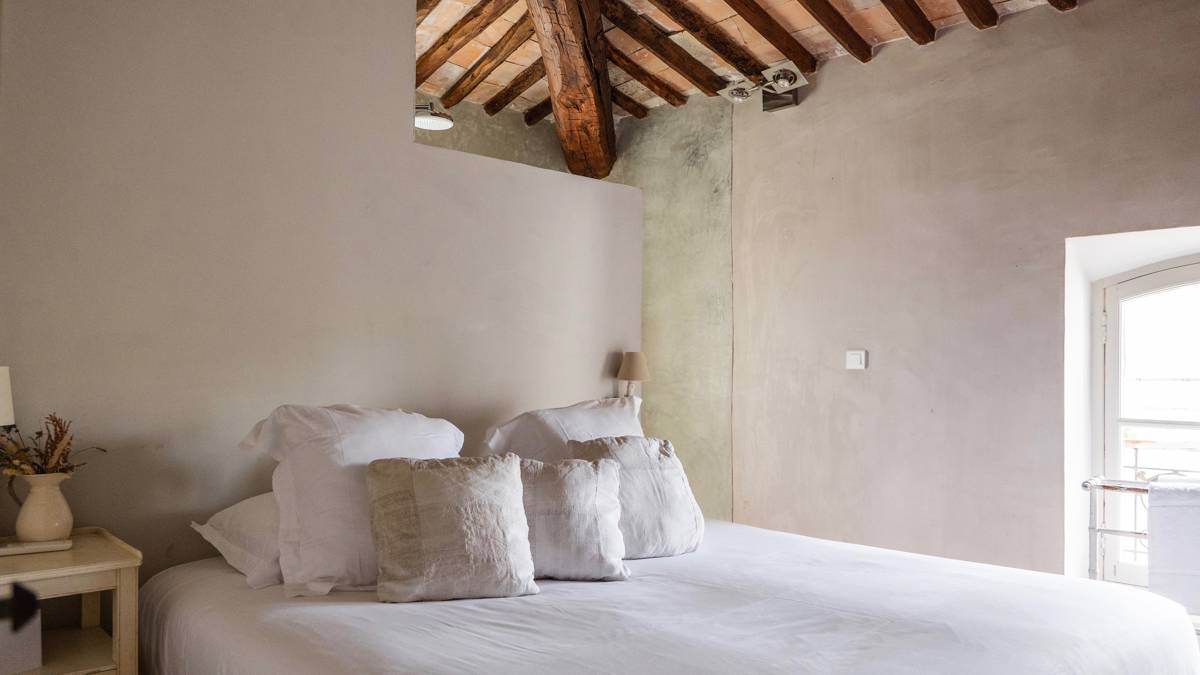 A properly organized bedroom features a cozy bed positioned close to the glass window.