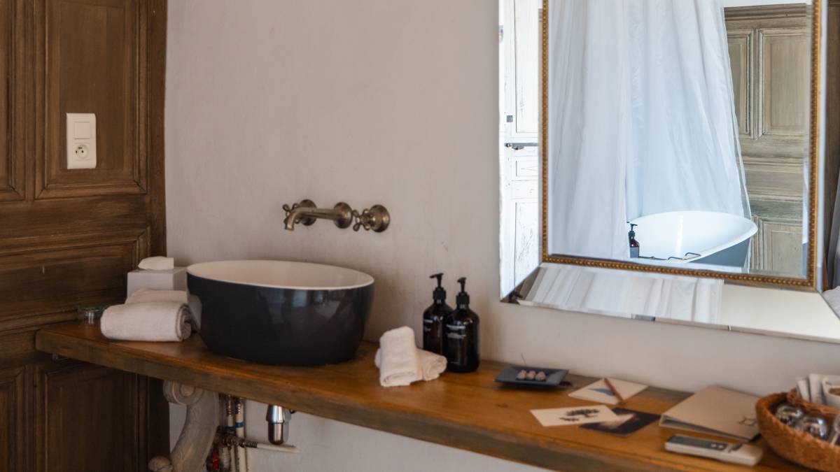 A uniquely designed sink sits left of the table, with bathing essentials neatly arranged atop.