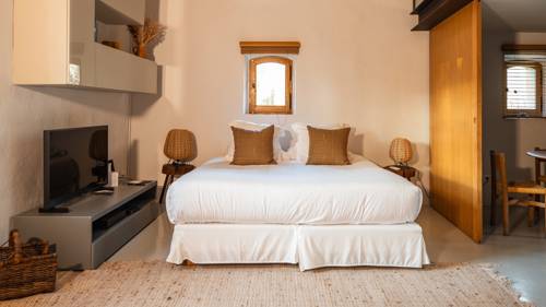 An organized bedroom featuring a cozy bed and a TV placed on the left table.