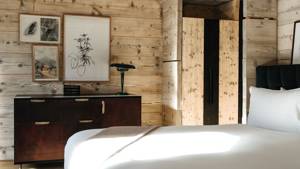 Different-sized portraits adorn a wooden-finished wall above a table with a unique lamp.