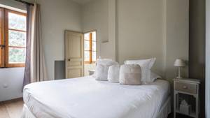 A tidy bedroom features a cozy bed with a side table holding a small lamp.