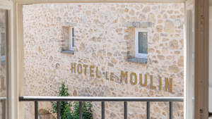 The name "HOTEL LE MOULIN" printed on the rough-textured wall is visible from the balcony.