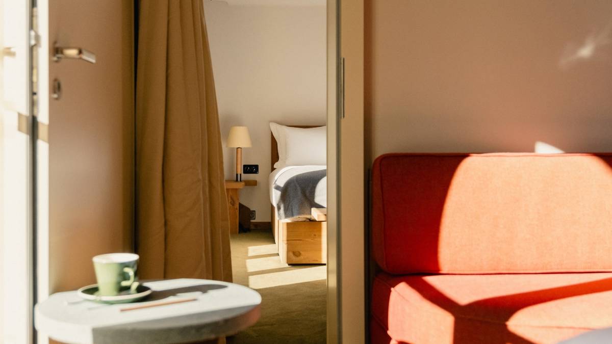 A red-colored sofa is placed by the bedroom door, with the bed visible inside.