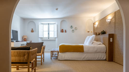 A well-organized bedroom features a cozy bed, a set of chairs, and a TV opposite.