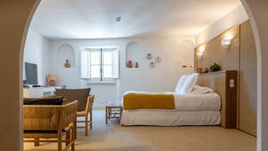 A well-organized bedroom features a cozy bed, a set of chairs, and a TV opposite.