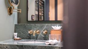 Salle de bains du Fitz Roy à Val Thorens, vasque en marbre vert, robinetterie laiton et miroir rétroéclairé