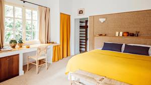 A well-organized bedroom features a cozy bed, a chair, and a table by the window.