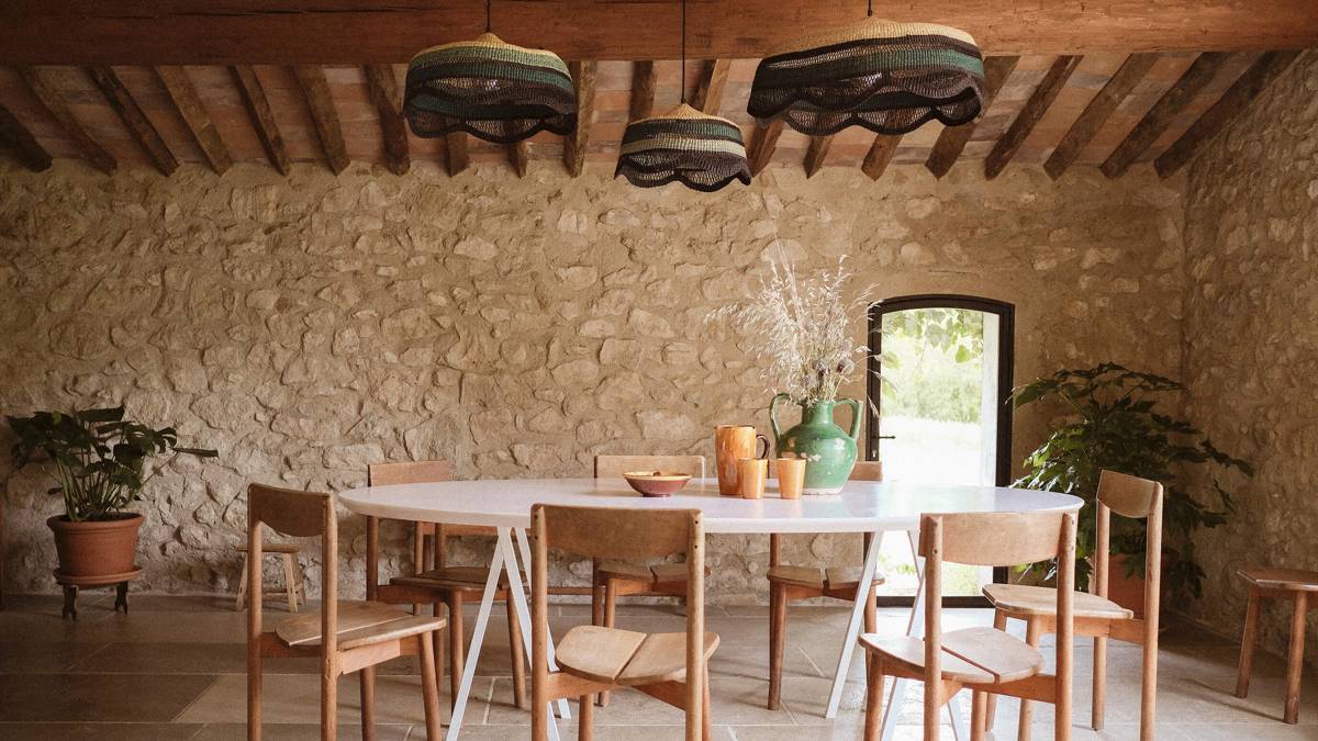 A neatly arranged dining space features an oval table, chairs, and three ceiling lamps above.