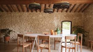 A neatly arranged dining space features an oval table, chairs, and three ceiling lamps above.