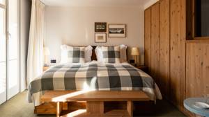 A well-organized bedroom showcases a cozy bed with two side tables and portraits above.
