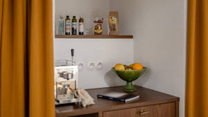 Properly arranged kitchen items in the shelves, with a fruit basket and coffee machine on table.