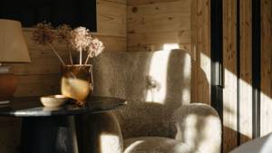 A feather-touch sofa is placed near the wooden-finished wall with a black coffee table.