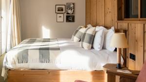 A well-organized bedroom features a cozy bed, a side table holding a lamp, and portraits above.