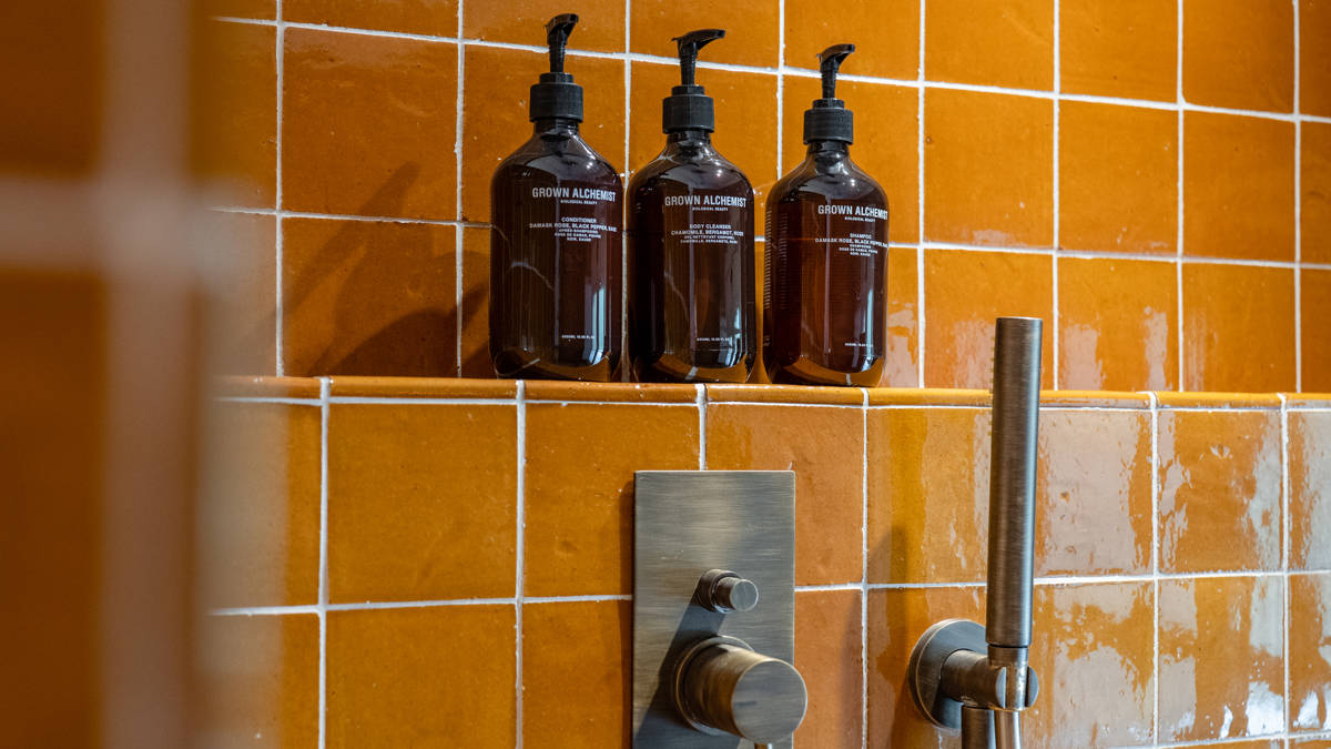 Three bathing bottles are properly arranged on the rack in the bathroom.