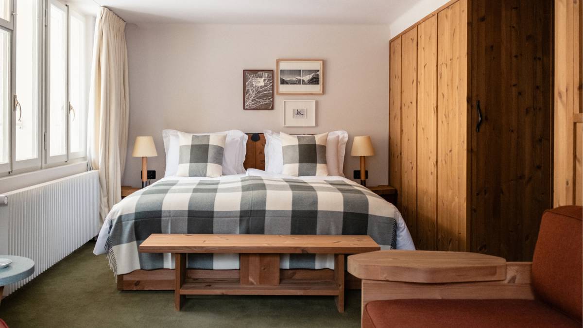 A well-organized bedroom features a cozy bed beside the wardrobe, with side tables and portraits above.