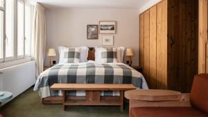 A well-organized bedroom features a cozy bed beside the wardrobe, with side tables and portraits above.
