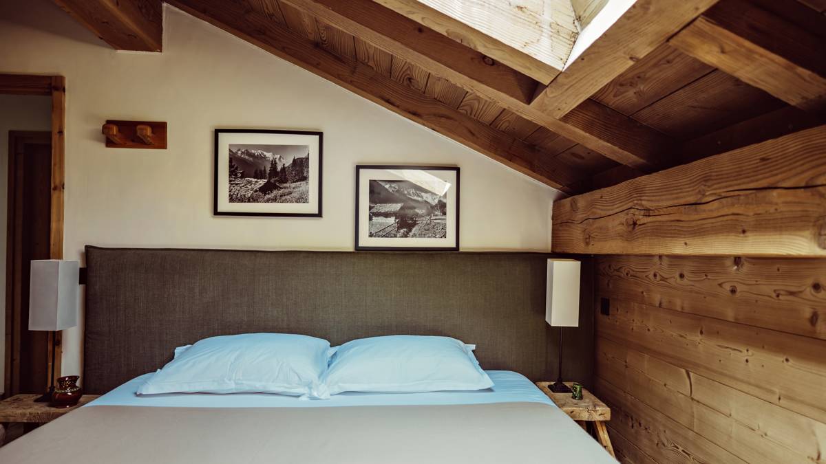 Two portraits are mounted above the bed, with side tables on both sides holding lamps.