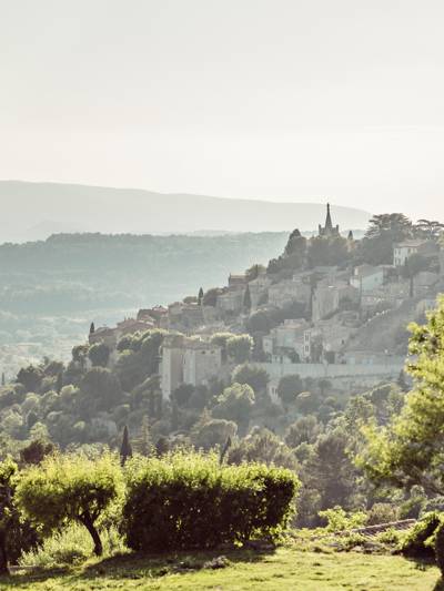 Vue panoramique sur le village perché de Bonnieux dans le Luberon, depuis le restaurant La Bergerie à Capelongue, entouré d'oliviers et de collines provençales