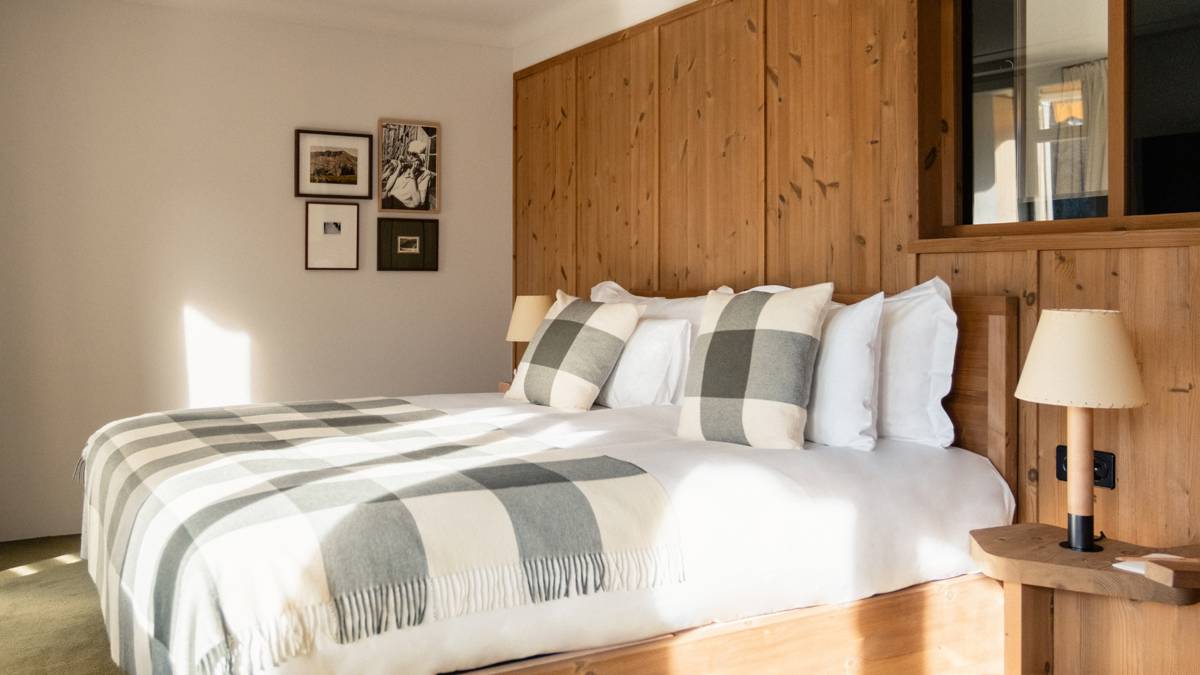 A well-organized bedroom features a cozy bed, a side table with a lamp, and portraits mounted above.