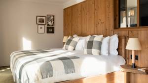 A well-organized bedroom features a cozy bed, a side table with a lamp, and portraits mounted above.